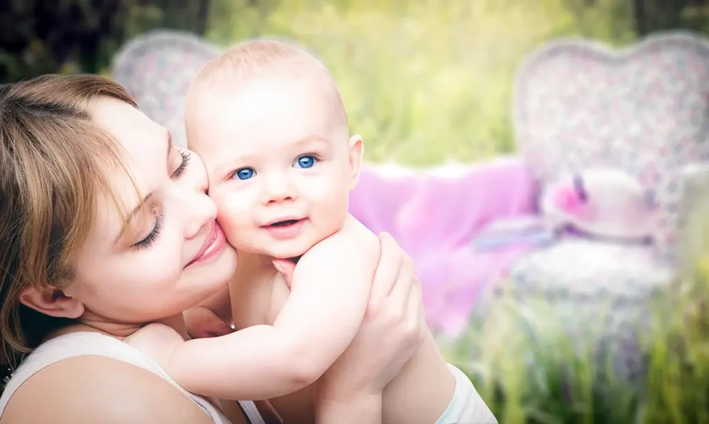 Eine glückliche junge Mutter hält Ihr Baby im Arm und schmust es Wange an Wange. Das Baby schaut glücklich und zufrieden