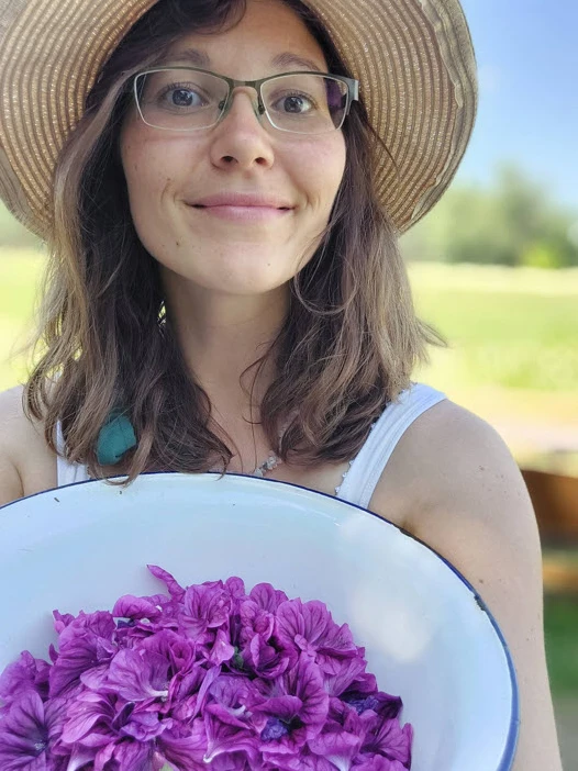 Portraitbild von Linda Jacob - deiner Stillberaterin. Linda schaut fröhlich und hält eine Schale mit Blüten in den Händen.